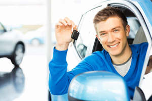 Young man sitting in new car with keys